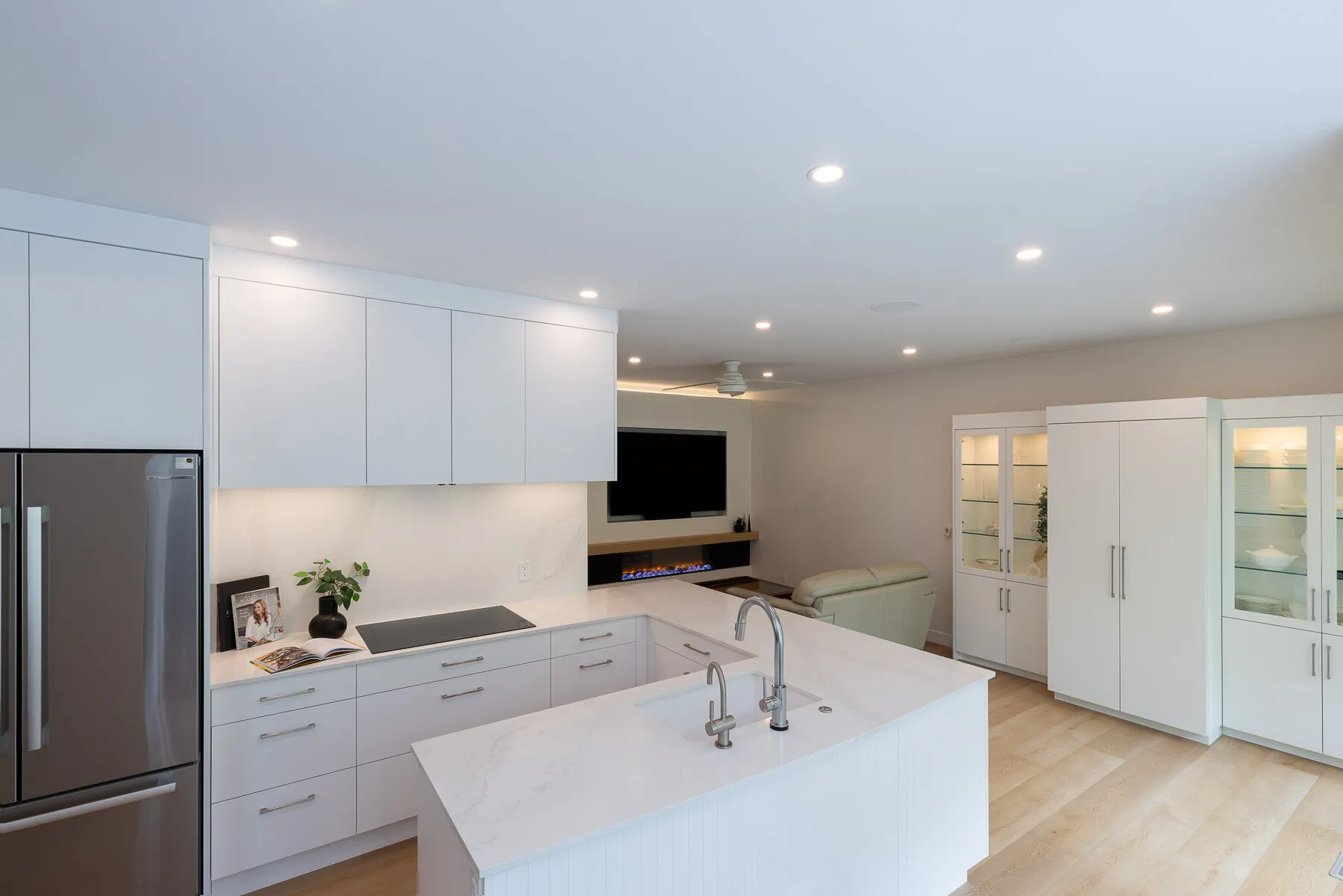Kitchen island with prep sink and black induction cooktop, facing the fireplace and TV wall.